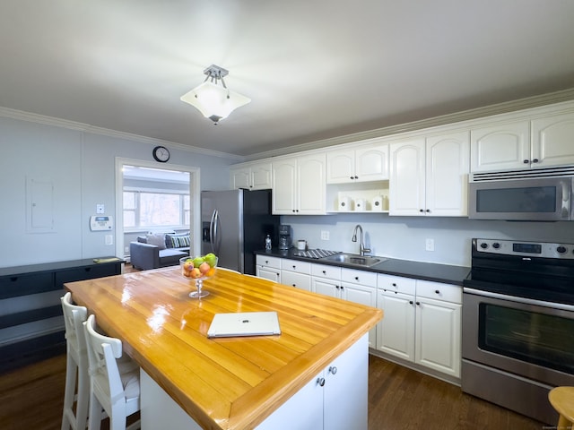 kitchen with wooden counters, ornamental molding, stainless steel appliances, and a sink