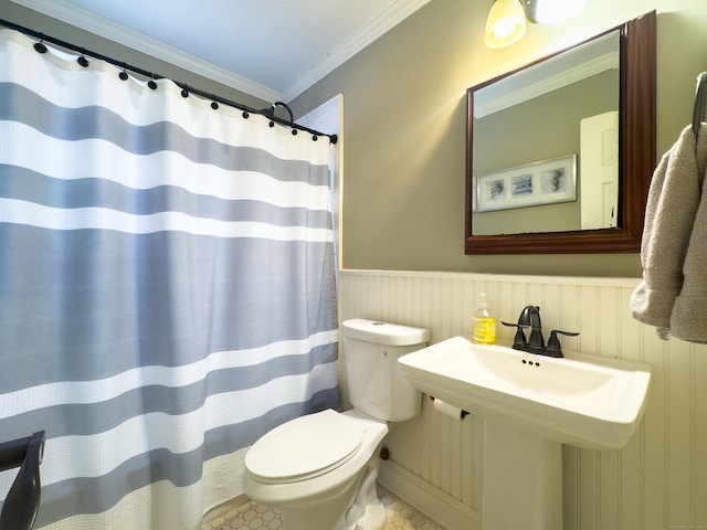 bathroom with a shower with shower curtain, wainscoting, toilet, and crown molding