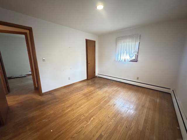 unfurnished bedroom with baseboards, a baseboard radiator, a baseboard heating unit, and hardwood / wood-style floors