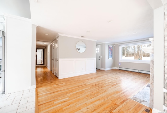 unfurnished room featuring light wood-style floors, visible vents, ornamental molding, and baseboard heating