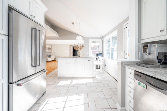 kitchen featuring lofted ceiling, light stone countertops, appliances with stainless steel finishes, and white cabinets