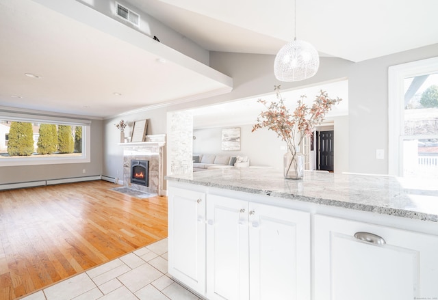 kitchen with open floor plan, white cabinets, plenty of natural light, and light stone countertops