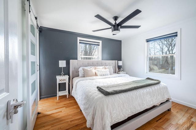 bedroom with ornamental molding, multiple windows, and light wood-type flooring