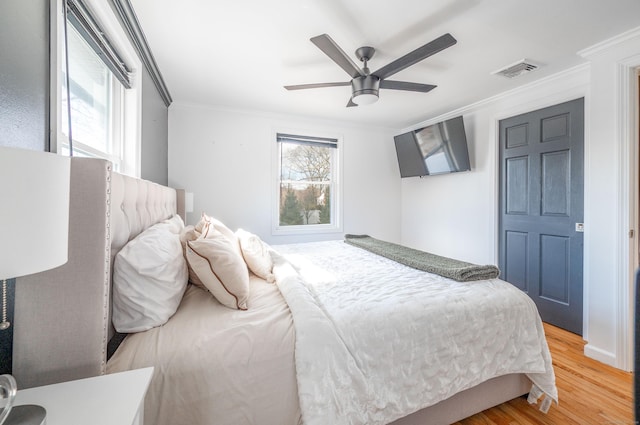 bedroom with light wood-type flooring, ceiling fan, visible vents, and ornamental molding