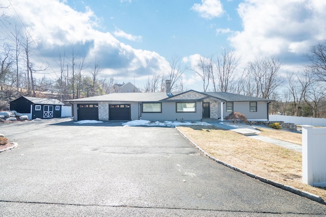 ranch-style house featuring a garage, aphalt driveway, and fence