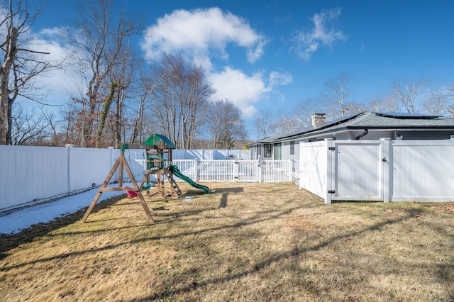 view of yard featuring a gate, a fenced backyard, and a playground