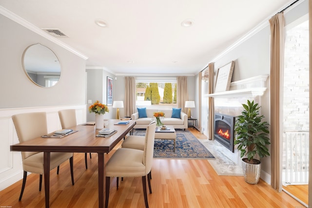 interior space with visible vents, light wood-style floors, a high end fireplace, and crown molding