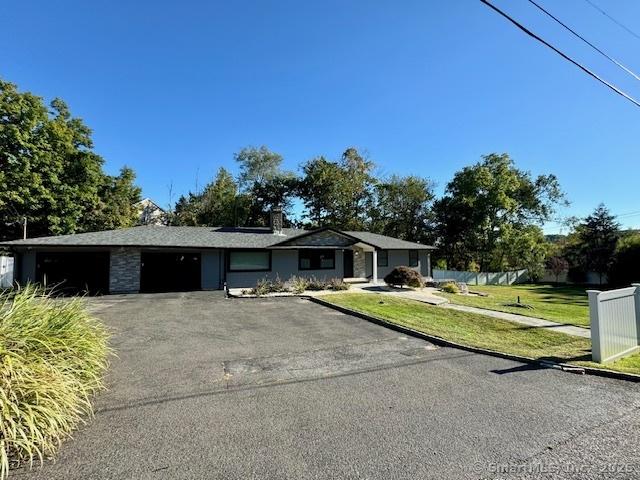 single story home with aphalt driveway, a front yard, fence, and an attached garage