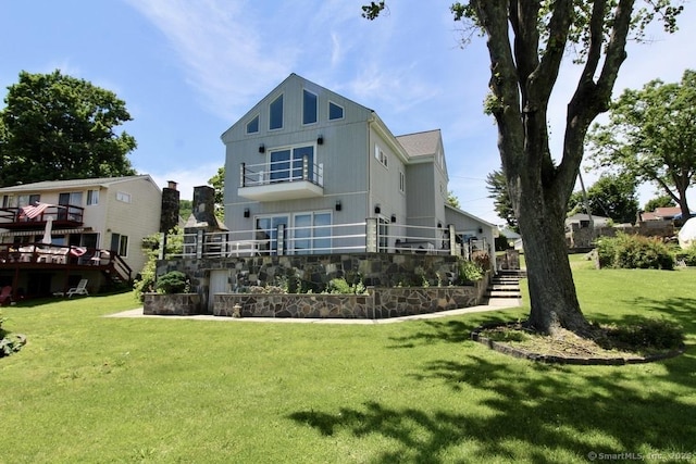 rear view of house featuring a deck, a yard, a balcony, and stairs