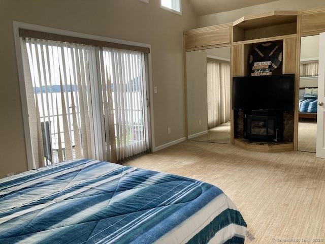 carpeted bedroom with a closet, a large fireplace, and baseboards