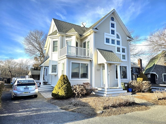 view of front of property with roof with shingles and a balcony