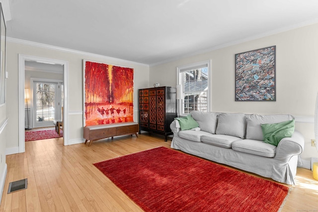 living room featuring visible vents, light wood-style floors, and ornamental molding