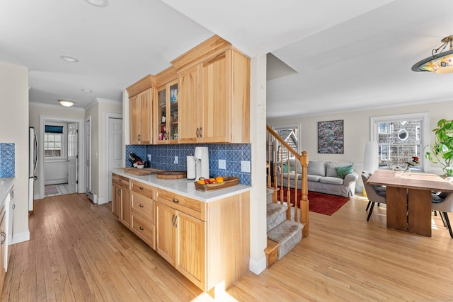 kitchen featuring light wood-type flooring, backsplash, freestanding refrigerator, crown molding, and light countertops