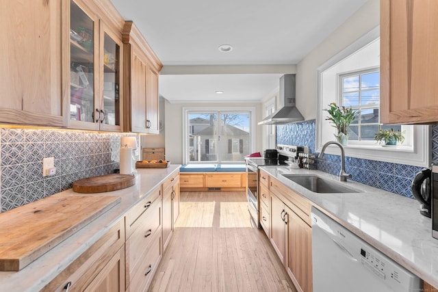 kitchen featuring light brown cabinets, a sink, stainless steel range with electric cooktop, wall chimney exhaust hood, and dishwasher