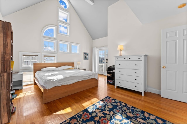 bedroom featuring baseboards, high vaulted ceiling, and hardwood / wood-style flooring