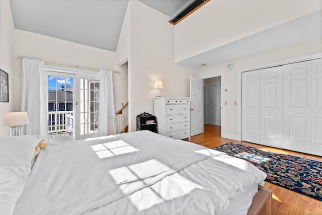 bedroom featuring a closet, high vaulted ceiling, baseboards, and wood finished floors