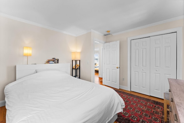 bedroom featuring a closet, baseboards, wood finished floors, and crown molding