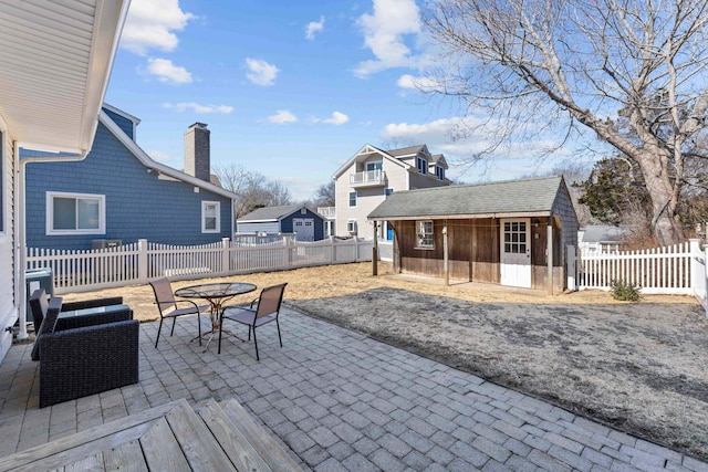 view of patio / terrace with an outbuilding, a fenced backyard, and outdoor dining space