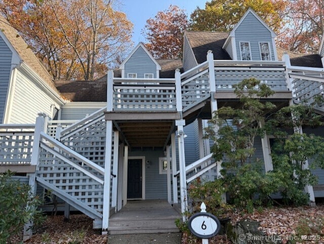 back of property with roof with shingles, a deck, and stairs