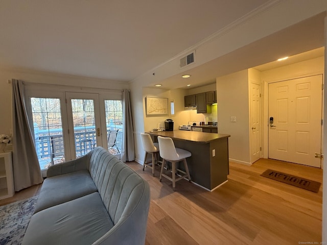 living room featuring baseboards, light wood-style flooring, visible vents, and crown molding