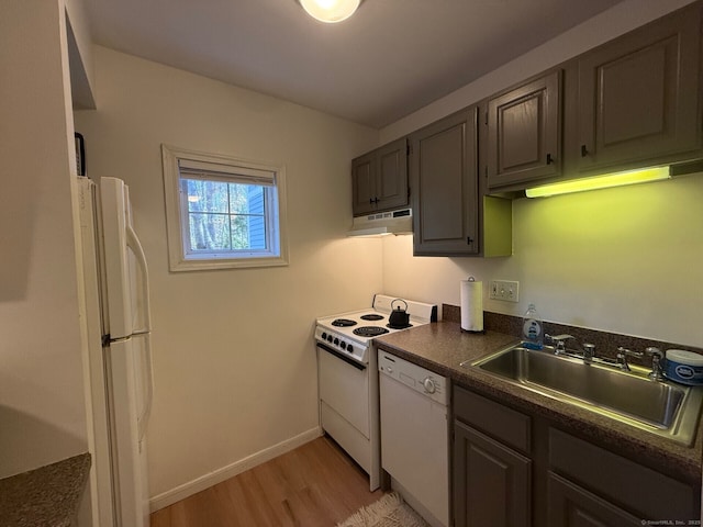 kitchen with range hood, dark countertops, light wood-style flooring, a sink, and white appliances