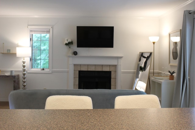 living room with ornamental molding and a tiled fireplace