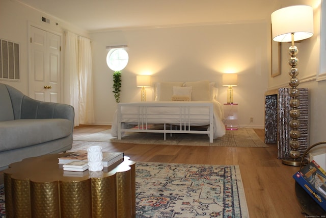 bedroom with baseboards, crown molding, visible vents, and wood finished floors