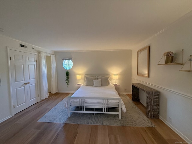 unfurnished bedroom featuring baseboards, visible vents, wood finished floors, and ornamental molding