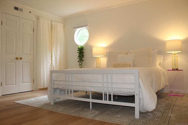 bedroom with crown molding, visible vents, and wood finished floors