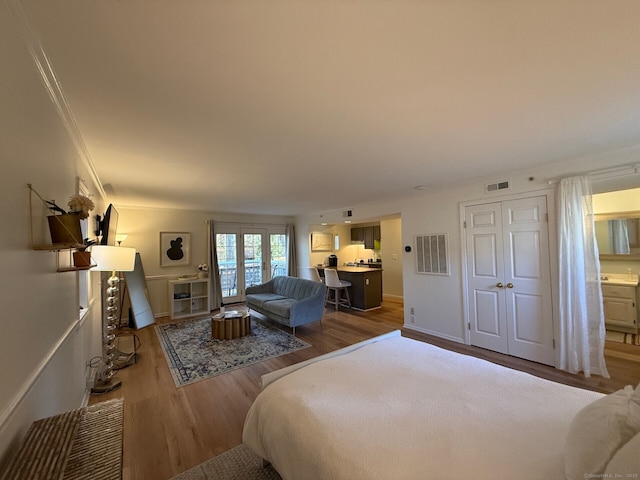 bedroom featuring visible vents, wood finished floors, and ornamental molding