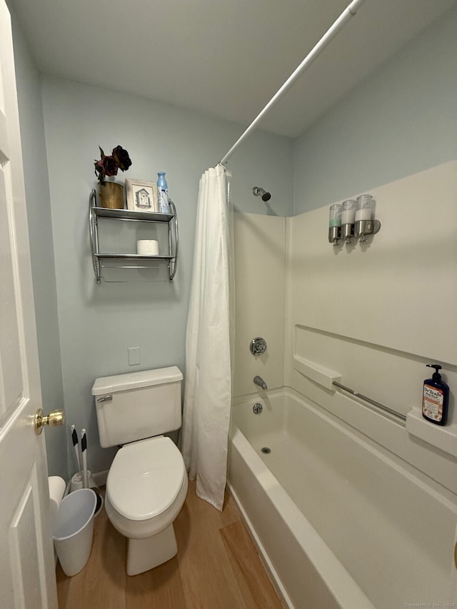 full bath with shower / tub combo, wood finished floors, and toilet