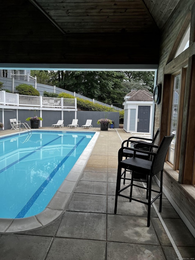 view of swimming pool featuring a fenced in pool, an outbuilding, a patio area, fence, and a shed