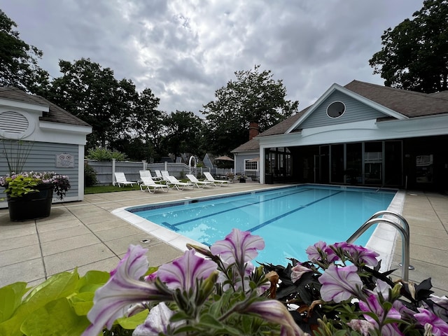 community pool with a sunroom, fence, and a patio