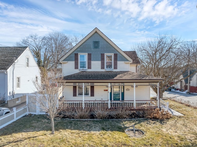 view of front of home with covered porch, a front lawn, a shingled roof, and fence