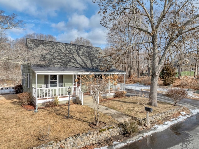 view of front facade with driveway, a porch, and roof with shingles