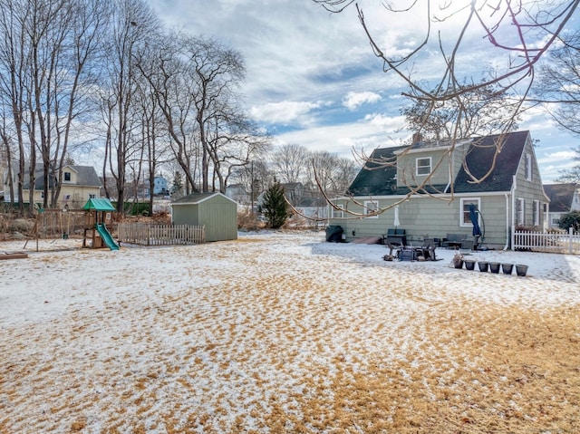 view of yard featuring an outbuilding, a playground, fence, and a storage shed