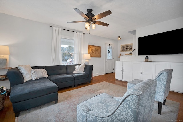 living area featuring ceiling fan, baseboards, and wood finished floors