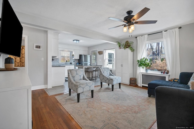 living room with a textured ceiling, ceiling fan, light wood-style flooring, and radiator