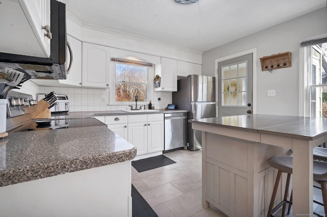 kitchen featuring stainless steel appliances, white cabinetry, a sink, and decorative backsplash