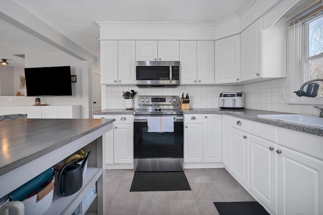 kitchen with white cabinets, decorative backsplash, stainless steel appliances, and a sink