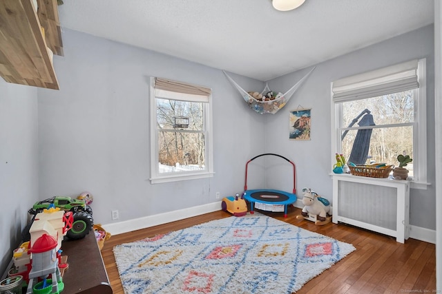 game room featuring hardwood / wood-style floors, radiator heating unit, and baseboards