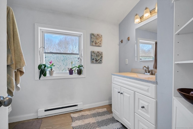 bathroom featuring a baseboard radiator, wood finished floors, vanity, and baseboards