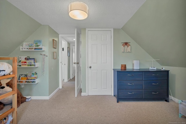 interior space featuring light carpet, a textured ceiling, and baseboards