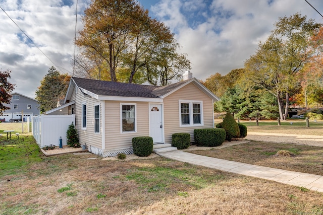 view of front facade featuring a shingled roof, fence, and a front yard