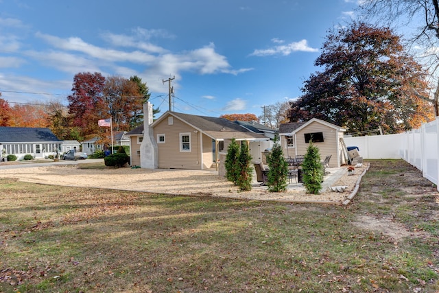 back of house featuring an outbuilding, a lawn, a patio area, and a fenced backyard