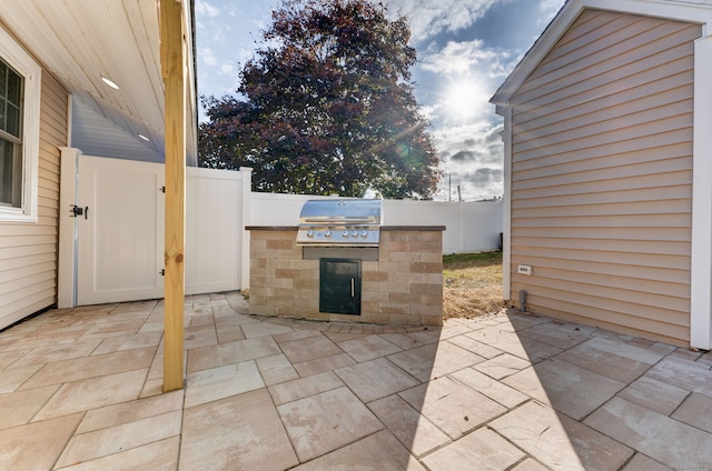 view of patio / terrace with an outdoor kitchen, grilling area, fence, and a gate