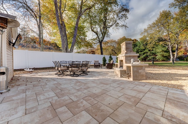 view of patio featuring fence, an outdoor fireplace, and outdoor dining area