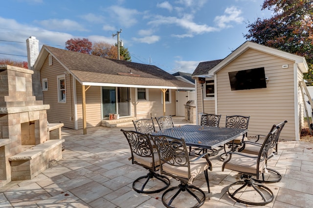 view of patio / terrace with outdoor dining space, an outdoor structure, and exterior fireplace