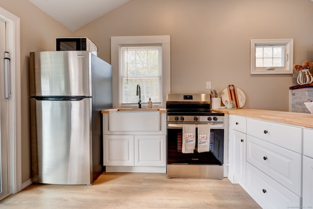 kitchen with lofted ceiling, stainless steel appliances, a sink, and light wood-style floors