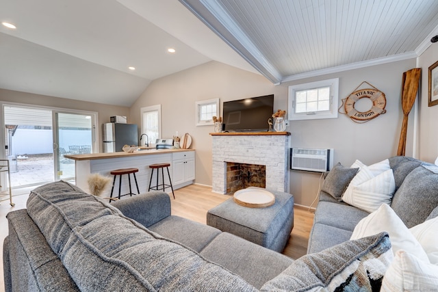 living area with light wood-style floors, vaulted ceiling, an AC wall unit, ornamental molding, and a brick fireplace